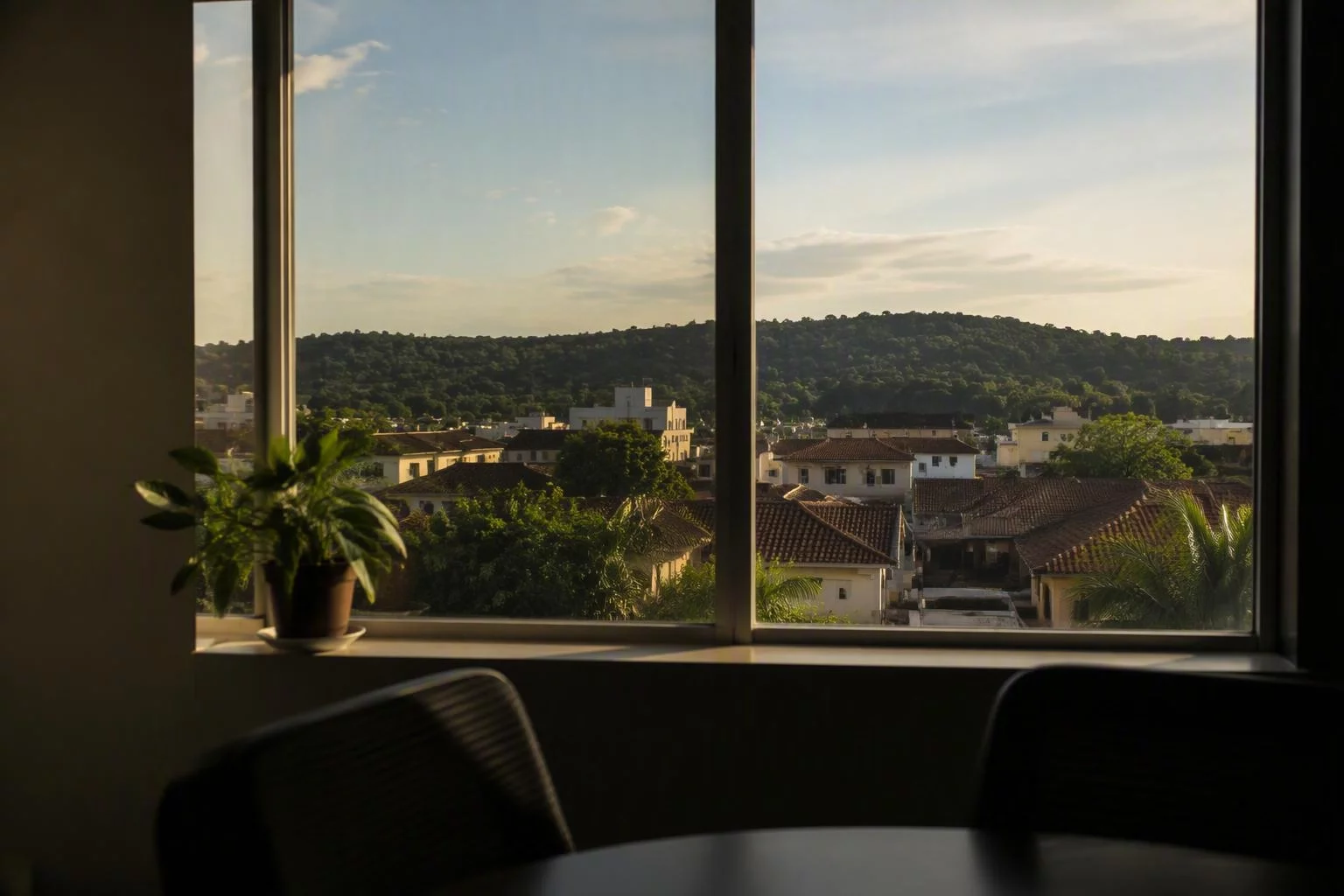 Janela da sala de reunião com a serra ao fundo, no fim da tarde